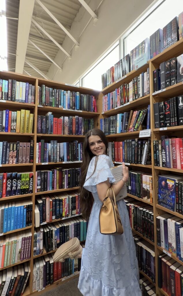 Alexzandra Stroud poses for a picture in front of bookshelves in a Texas public library
