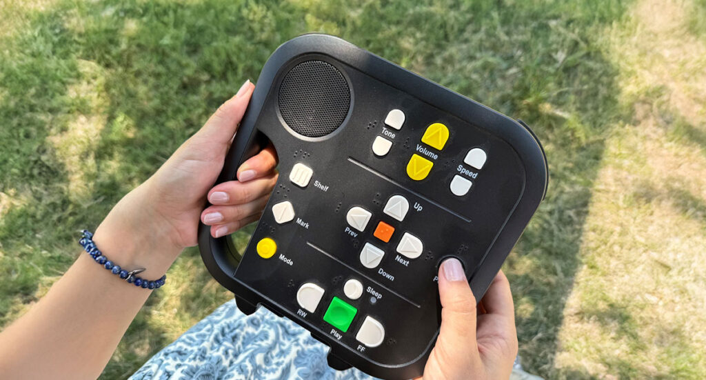 A patron holds a device used to listen to books from the Talking Book Program