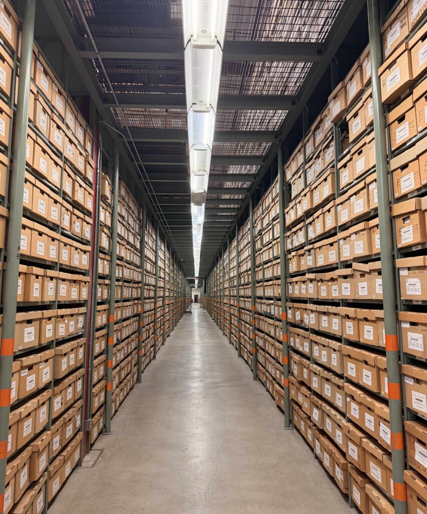 A long corridor filled with boxes on shelves from floor to ceiling. 