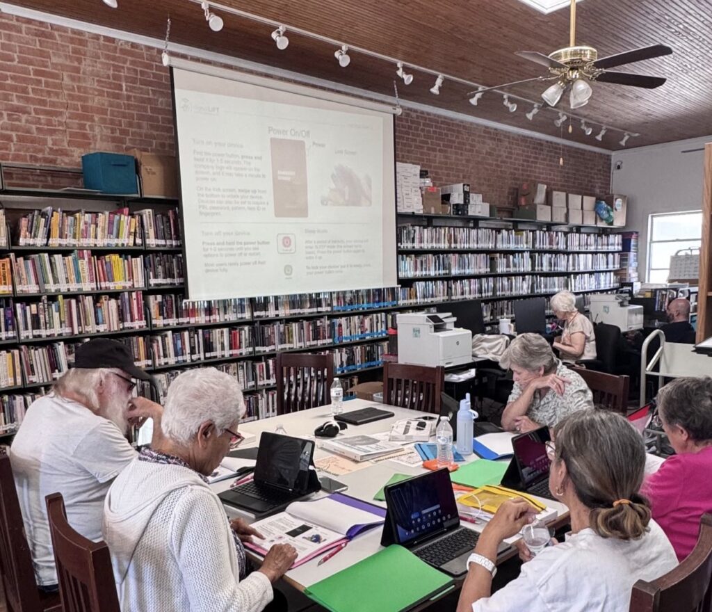 A group of senior citizens take part in a digital literacy class held at Martindale Community Library, sitting at tables looking at laptop screens