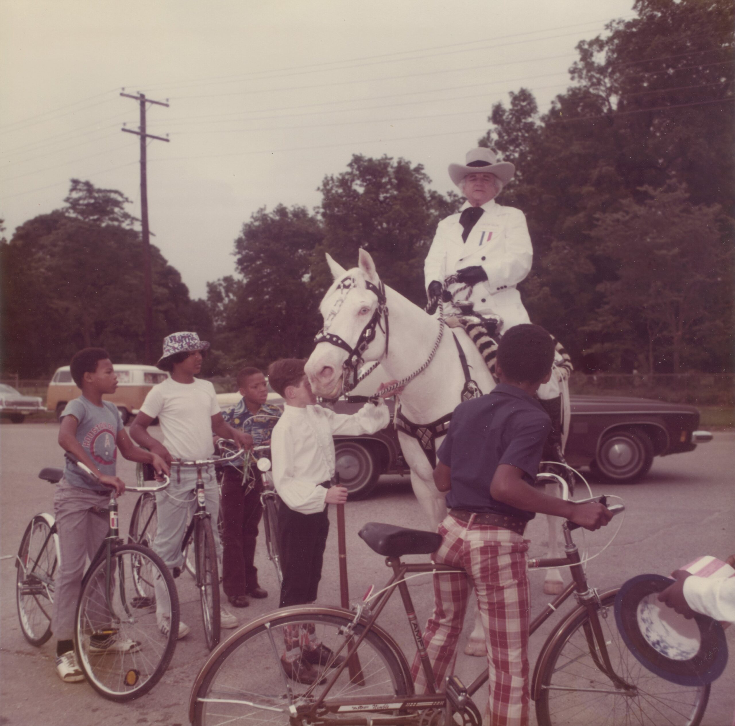 governor bill daniel dressed as sam houston in white suit and hat and sitting on a white horse. Several children on bicycles surround Daniel.