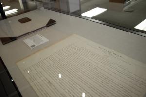 Photo of Constitution in exhibit display case, showing large document with handwriting